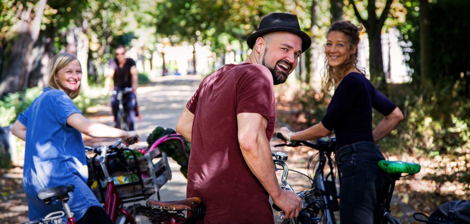 Gruppe von fröhlichen Radfahrern, die sich im Stehen unterhalten und in die Kamera blicken