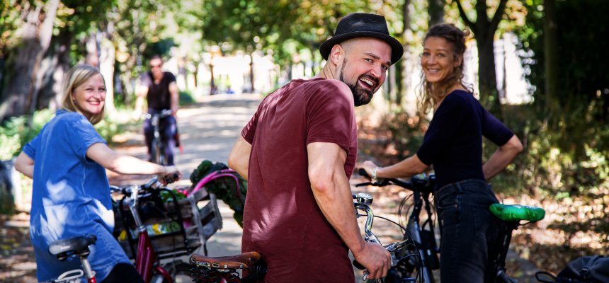 Gruppe von fröhlichen Radfahrern, die sich im Stehen unterhalten und in die Kamera blicken