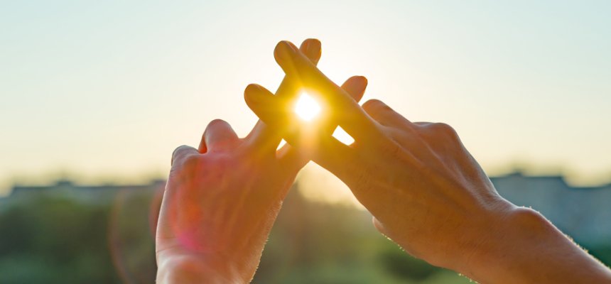 Zwei Hände formen einen Hashtag in Richtung Sonne.