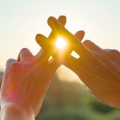 Zwei Hände formen einen Hashtag in Richtung Sonne.