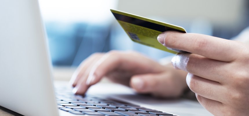 Hände benutzen Computer und halten eine Kreditkarte