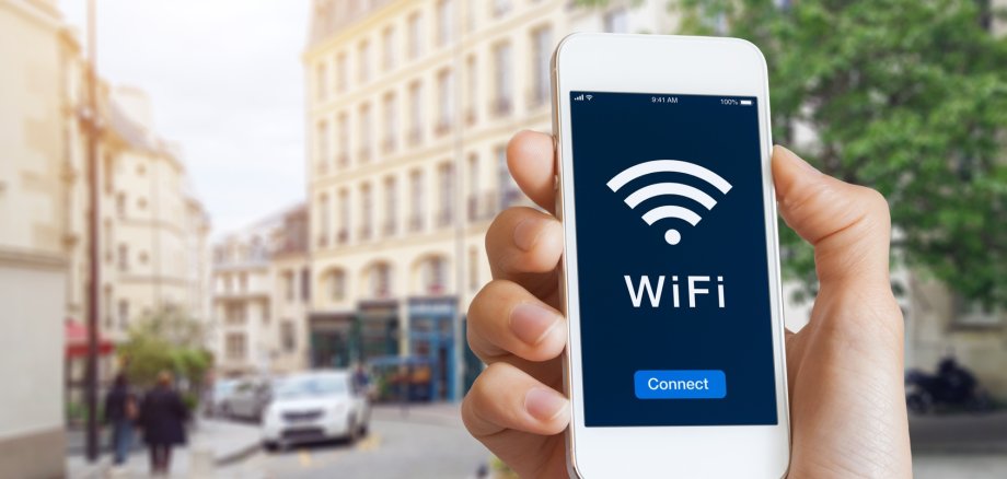 Connection to public WiFi hotspot in the city street to access internet on smartphone, concept about wireless technology and travel, close-up of hand