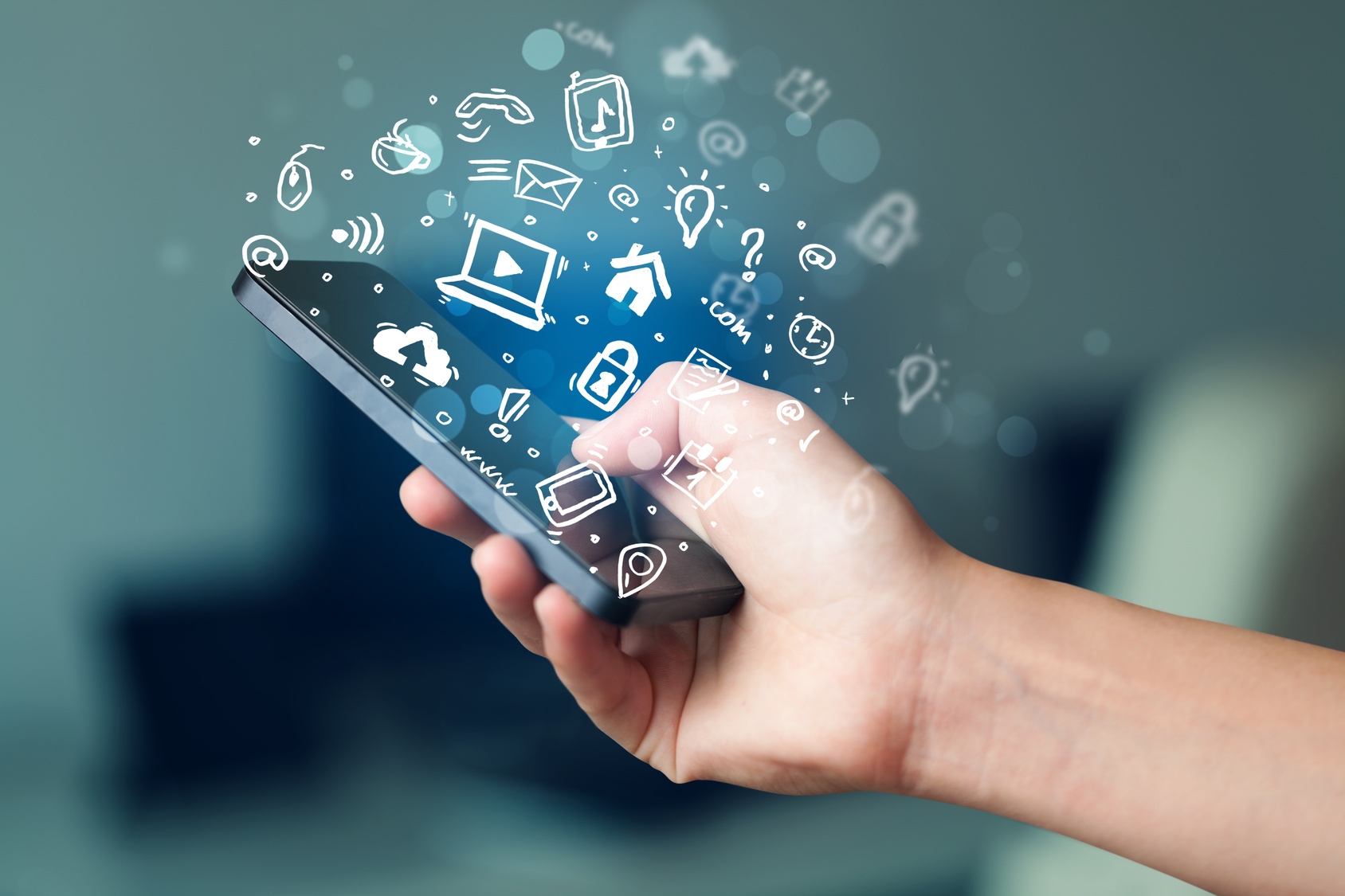 Eine Hand hält ein Handy aus dem Medien Symbole herrauskommen.