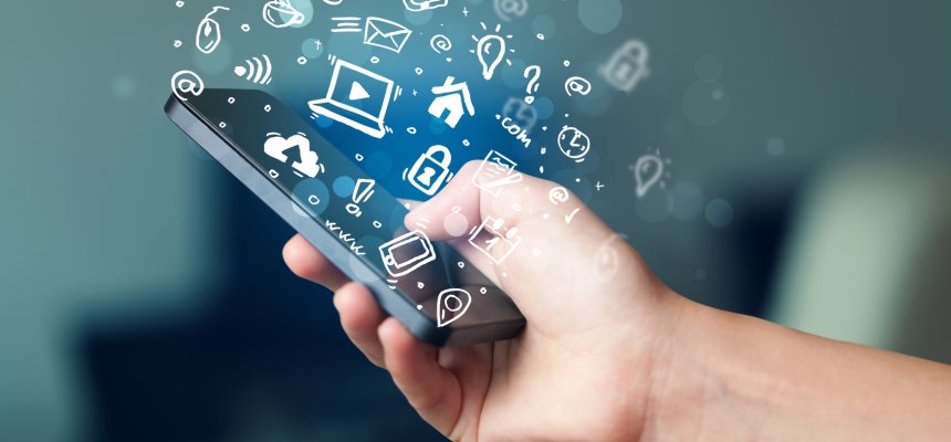 Hand holding smartphone with media icons and symbol Eine Hand hält ein Handy aus dem Medien Symbole herrauskommen.