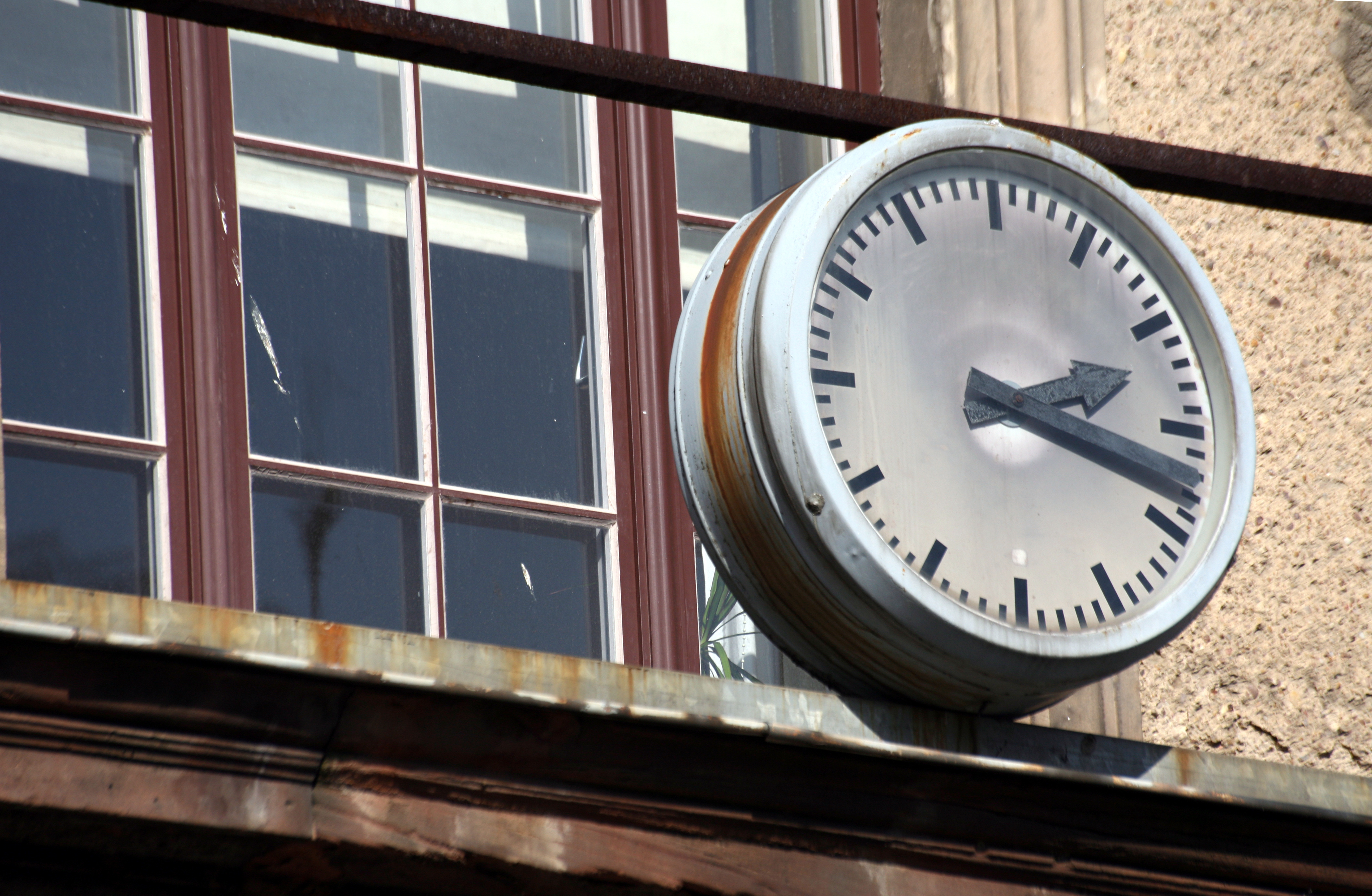 Vergammelte Uhr an einem maroden Schulgebäude