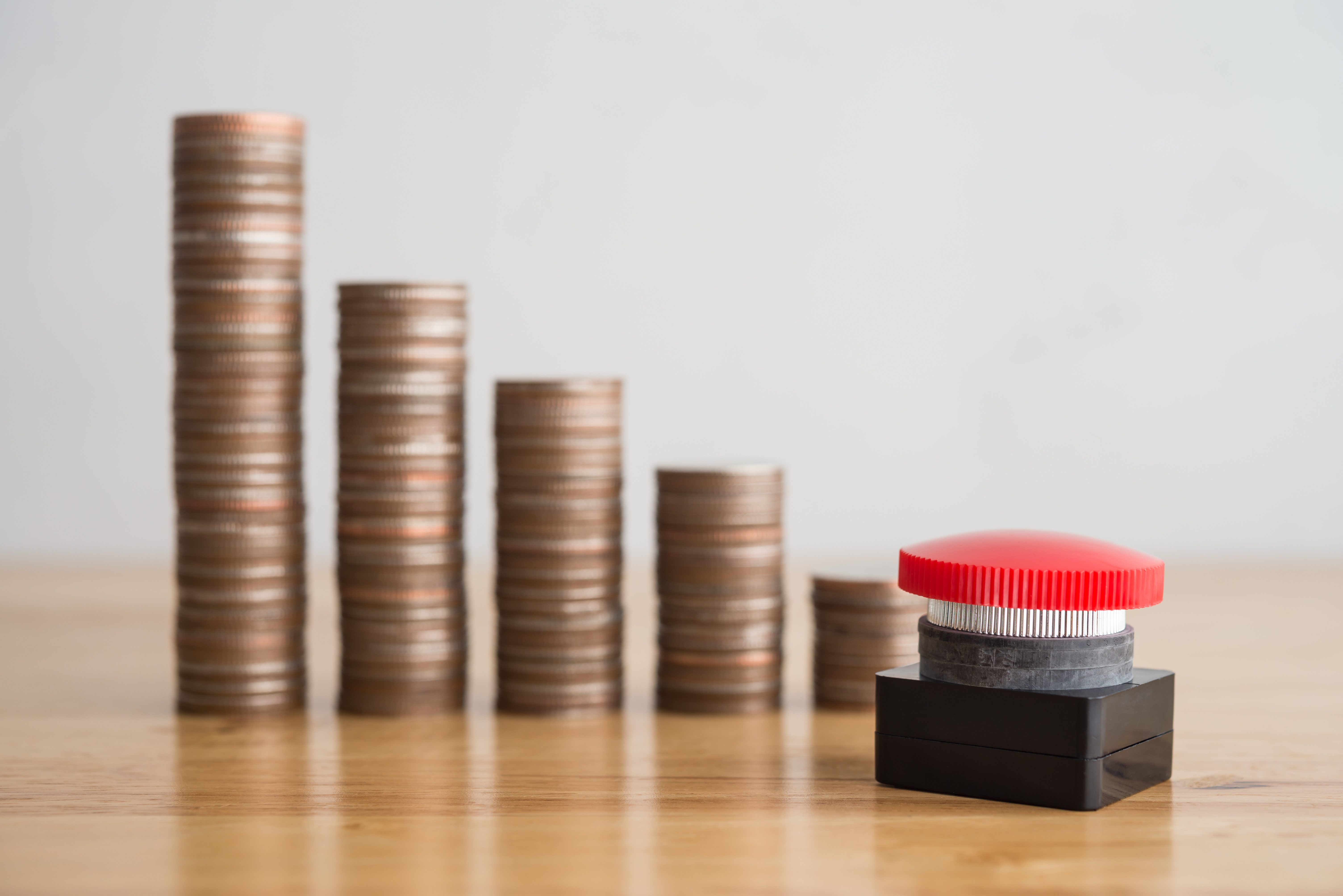 Finanznot der Kommunen Mehrere Kleingeldstapel aufgereiht, die nach rechts immer kleiner werden. Davor steht ein roter Knopf.