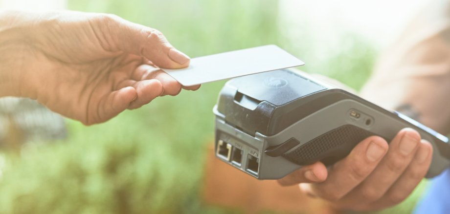 Woman paying contactless with card to male seller