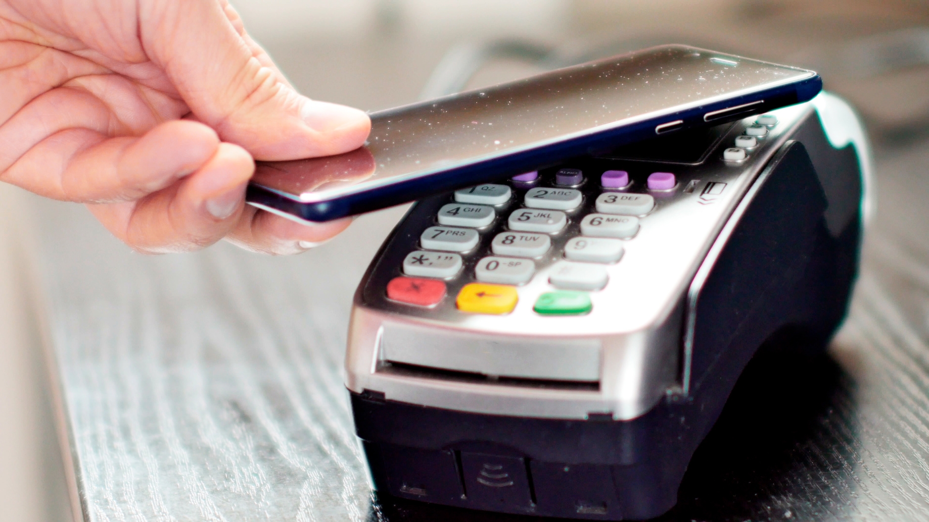 Customer paying with NFC technology by mobile phone on terminal. Kreditkarte bezahlt Kontaktlos