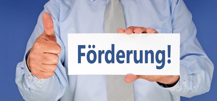 Man mit Hemd  mit Schild in der Hand auf dem Schild steht ,,förderung"