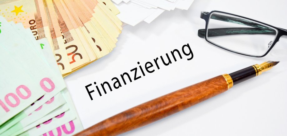 Geld, Stift und Schild mit Finanzierung