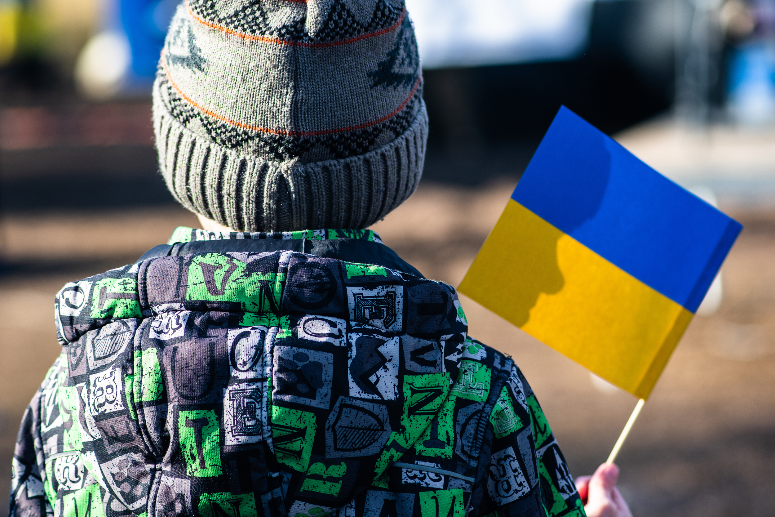 Child or kid with winter clothes, hat and Ukrainian flag, profile of the child is on the flag. War in Ukraine, caused by Putin and Russia