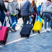 Ukrainische Flüchtlinge verlassen die Ukraine. Menschen mit Rollkoffern gehen hintereinander her.