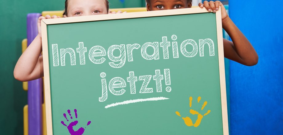 Zwei Kinder halten Tafel mit dem Spruch "Integration jetzt!" im Kindergarten