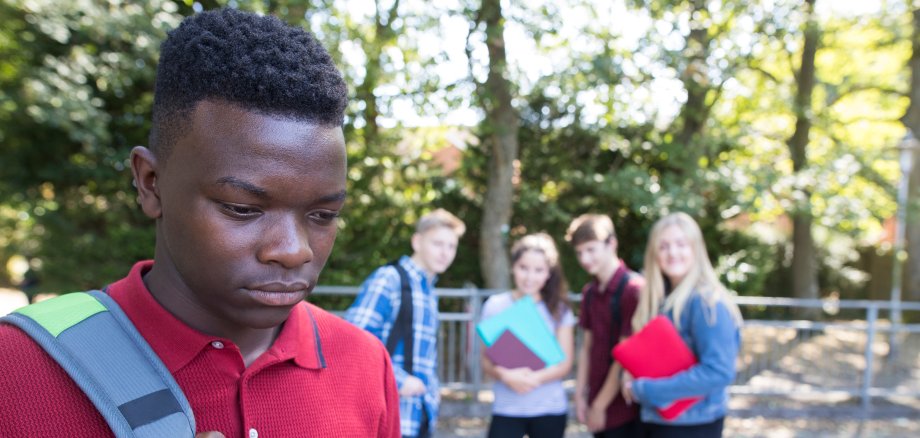 Unglücklicher Teenager, über den Schulfreunde klatschen.