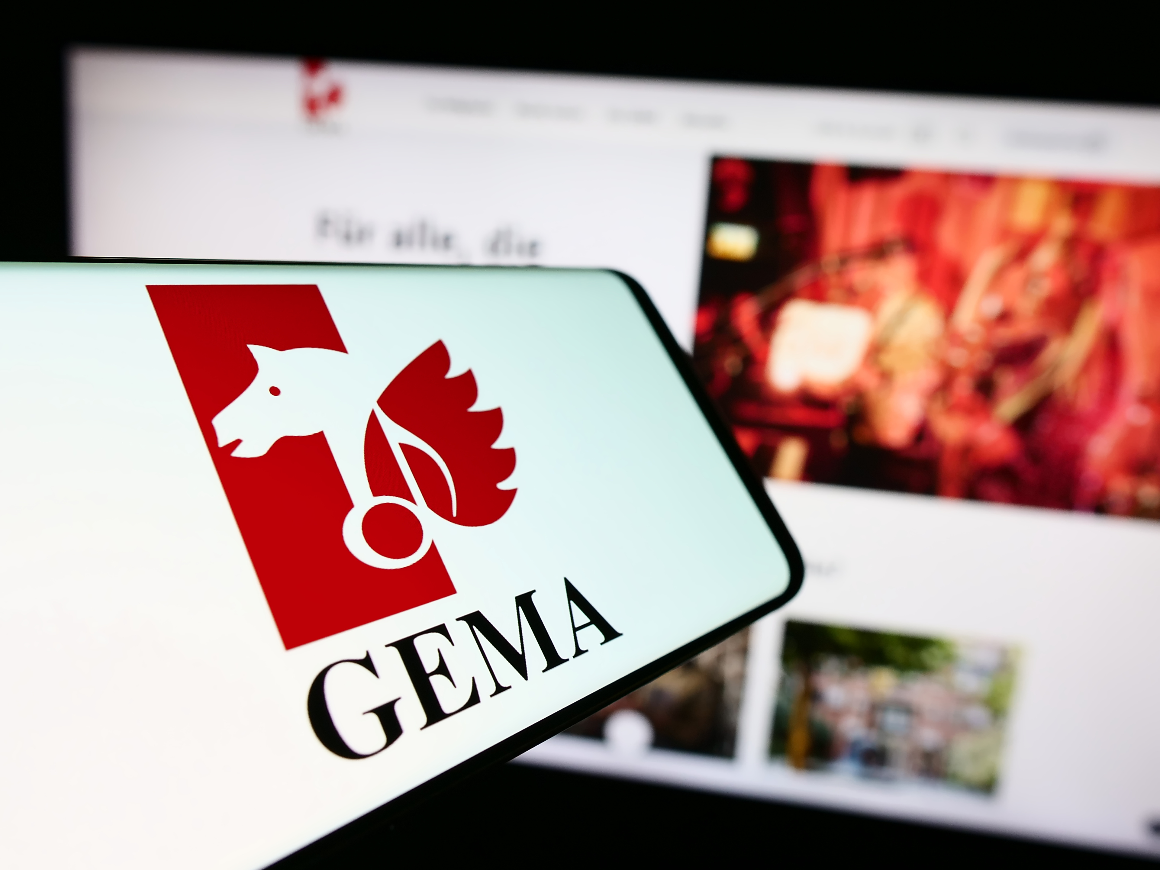 Mobiltelefon mit Logo der deutschen Verwertungsgesellschaft GEMA vor deren Website.
