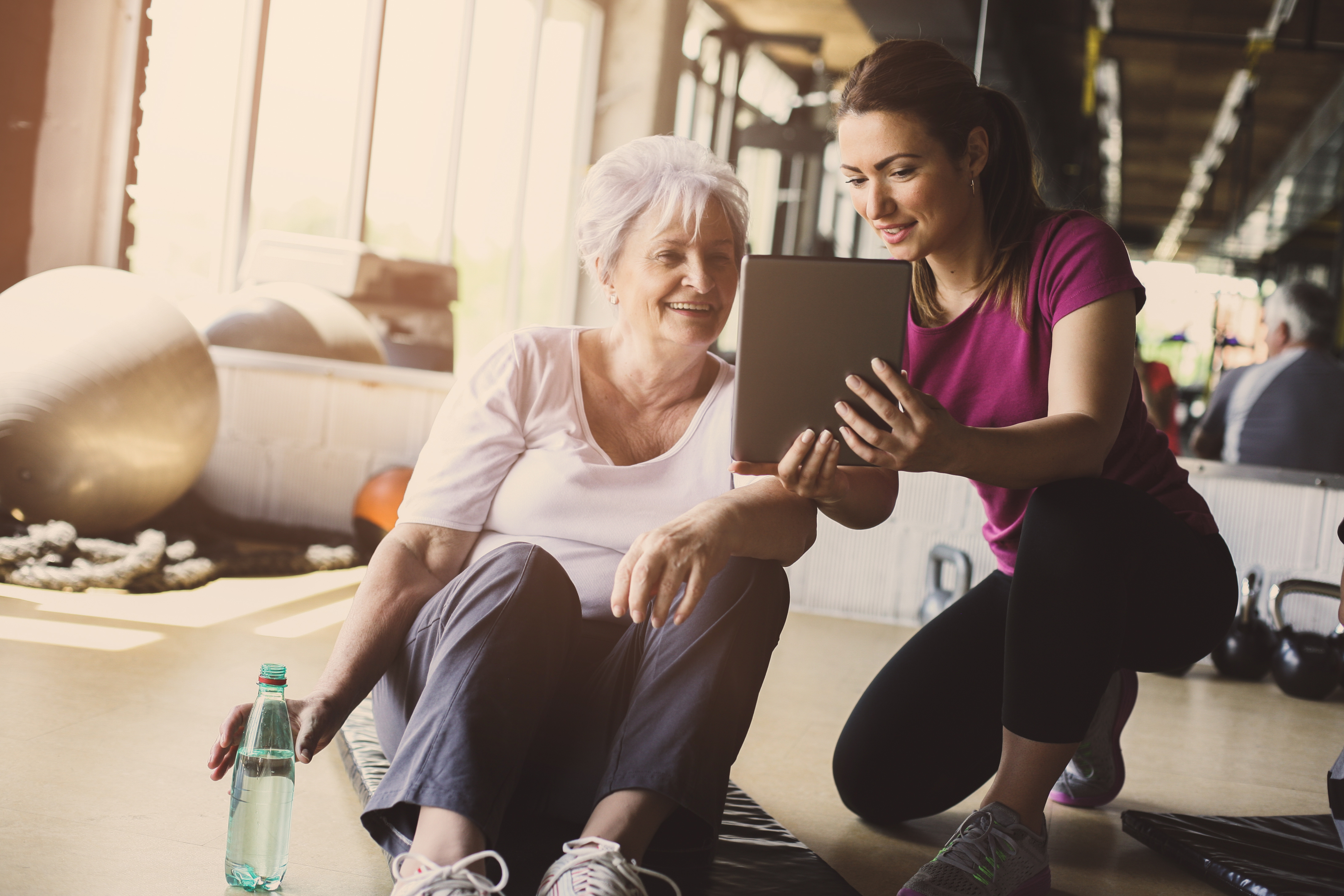 Senior woman workout in rehabilitation center. Personal trainer showing something on digital tablet. © liderina - stock.adobe.com