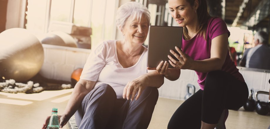 Senior woman workout in rehabilitation center. Personal trainer showing something on digital tablet. © liderina - stock.adobe.com