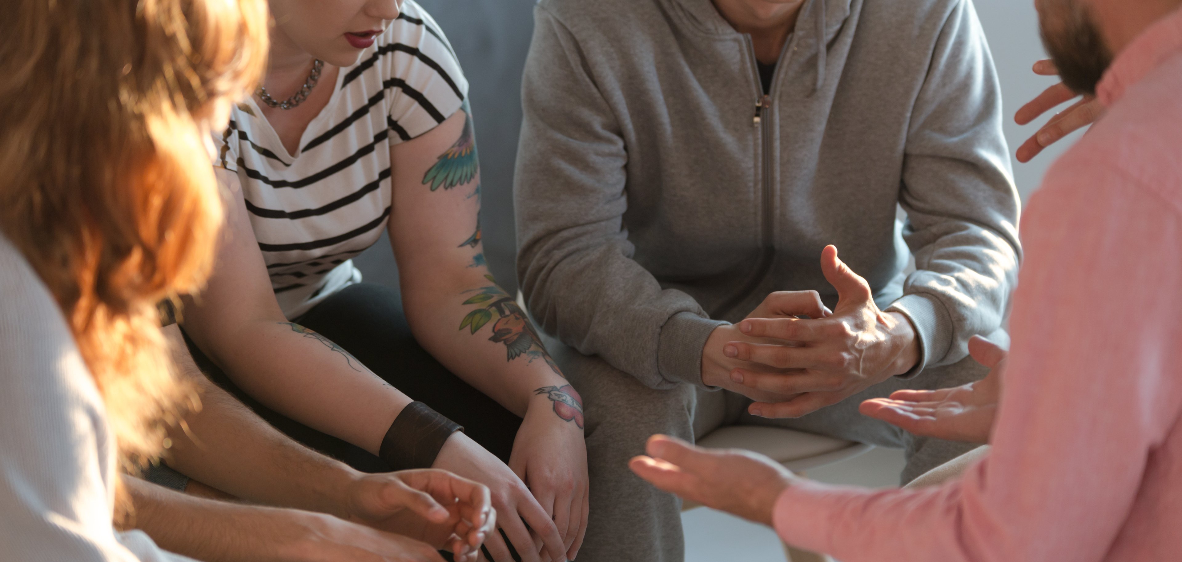 Rebellischer Jugendlicher mit Tätowierungen spricht während eines Therapiegesprächs über seine Probleme.
