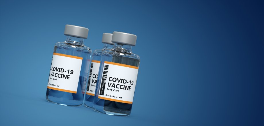 Drei Fläschchen mit Covid-19 Impfstoff vor blauem Hintergrund drei Fläschchen mit Covid-19 Impfstoff vor blauem Hintergrund