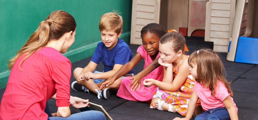 Gruppe Kinder redet über ein Buch im Kindergarten mit der Erzieherin