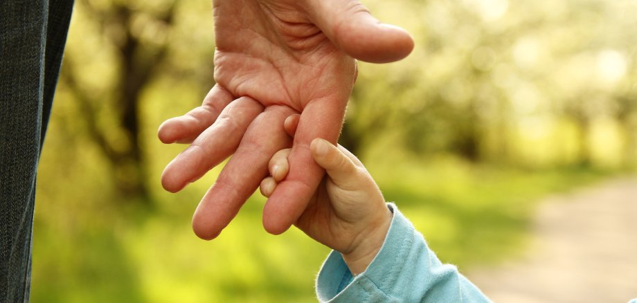 parent holds the hand of a small child Elternteil hält Kinderhand