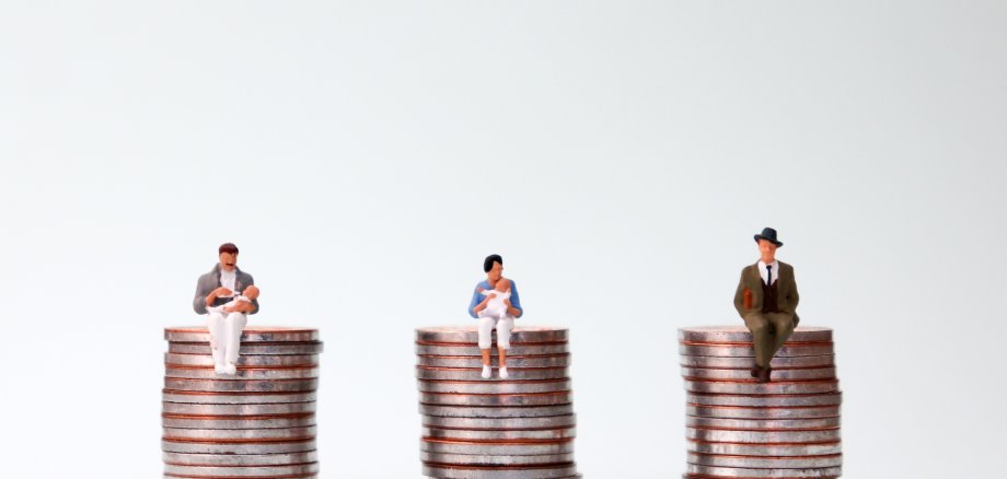 An equal pay concept. Miniature people sitting in the same height pile of coins. menschen auf Geld