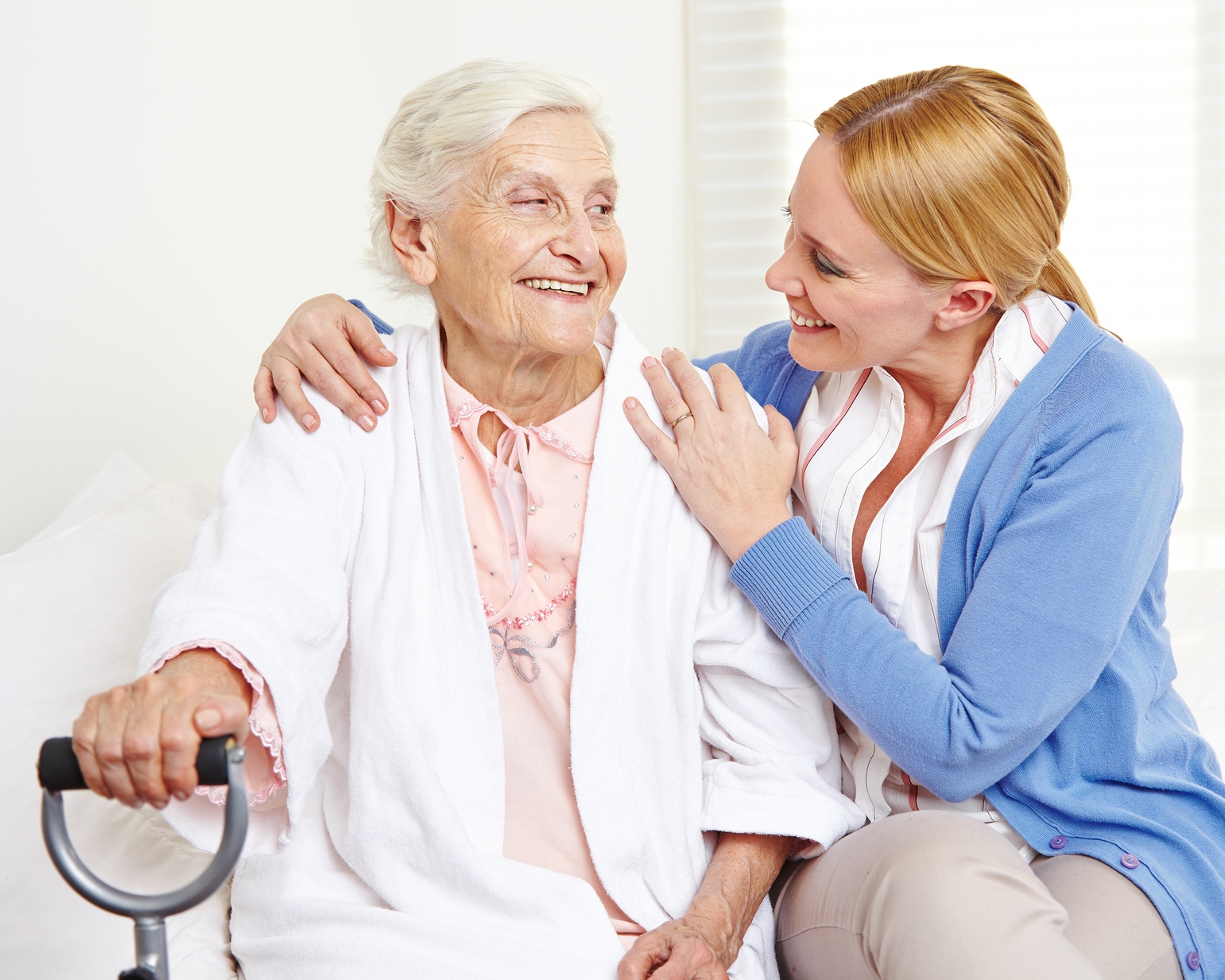 Lachende Seniorin zu Hause schaut ihre Tochter an
