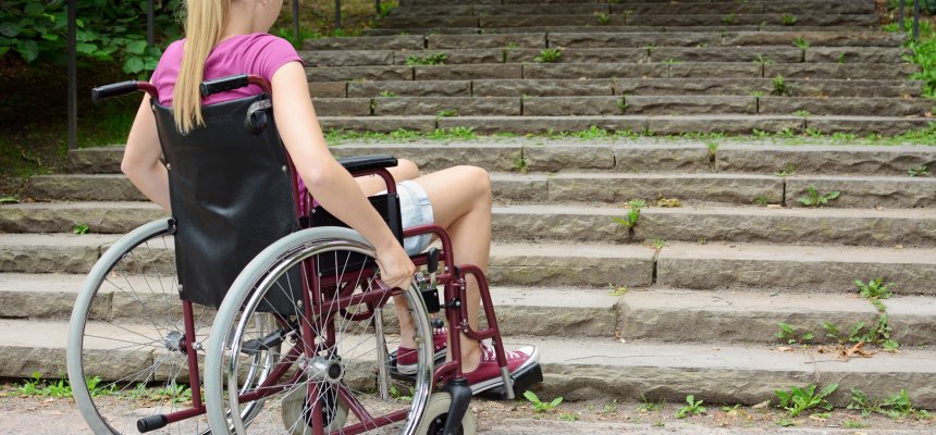 Frau im Rollstuhl vor Treppe als Hindernis