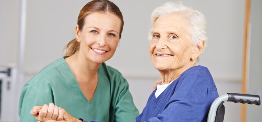 Altenpflege durch lächelnde Krankenschwester bei einer glücklichen Seniorin