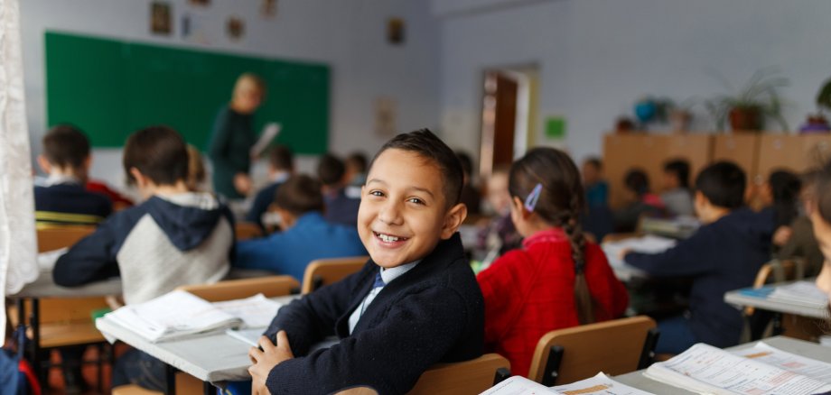 Glücklicher Schüler in voll besetzem Klassenraum