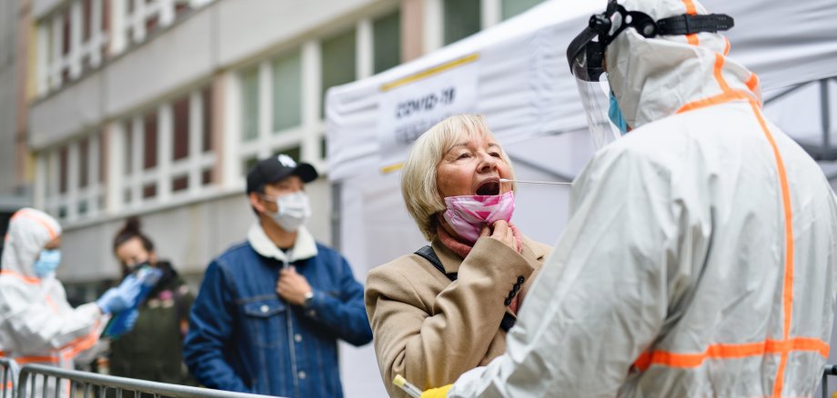 Menschen, die bei einem Freiluft Covid-19 Testzentrum anstehen. 