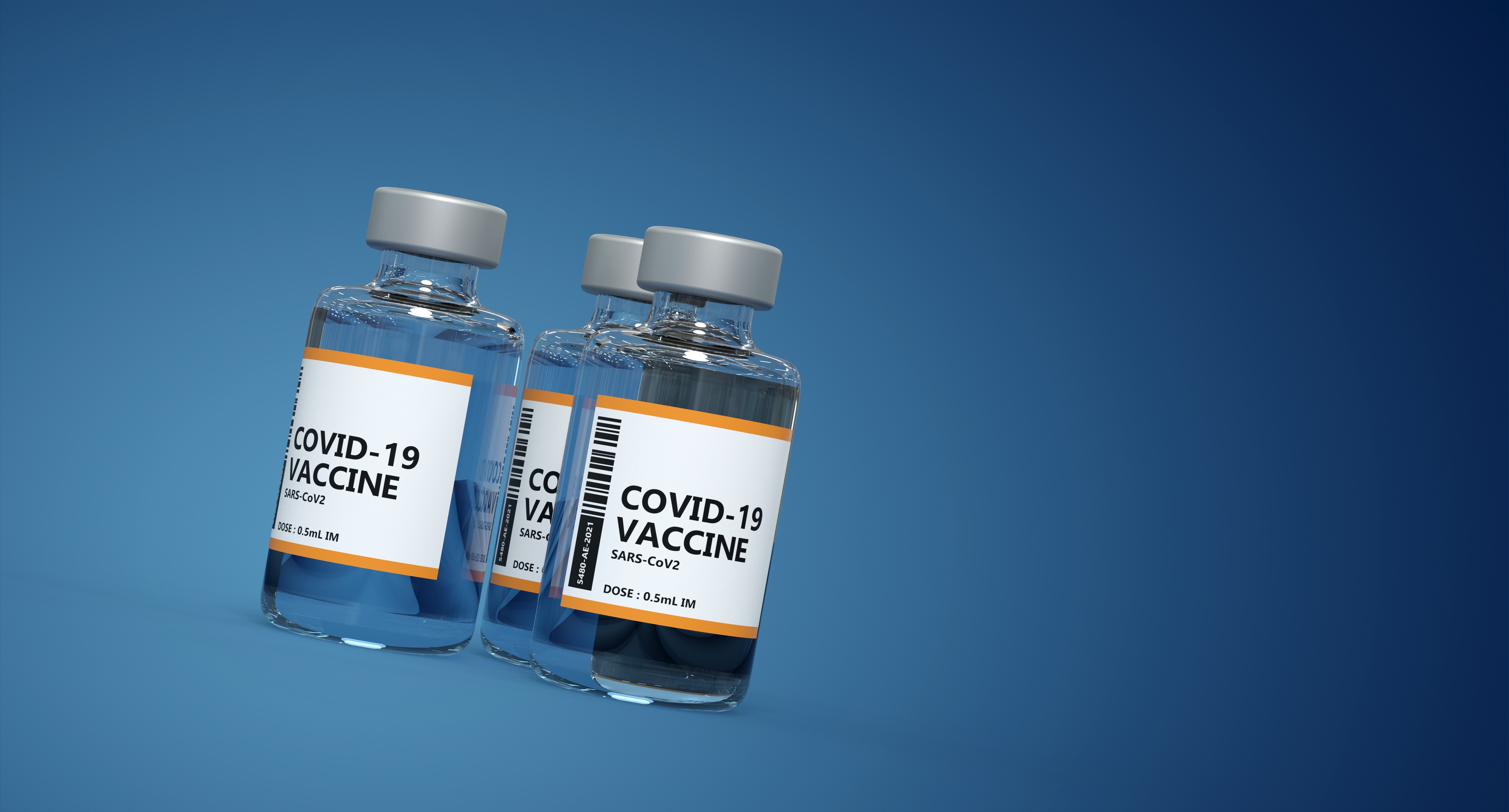drei Fläschchen mit Covid-19 Impfstoff vor blauem Hintergrund