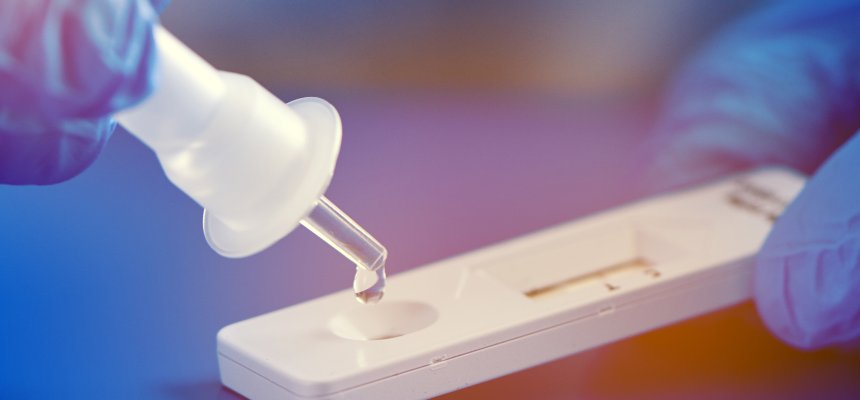 Großaufnahme eines Corona Schnellteststreifens mit blauen OP-Handschuhen