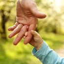 Elternteil hält Kinderhand