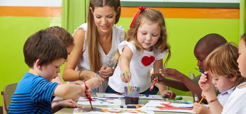 Viele Kinder malen mit Farbe zusammen mit Erzieher im Kindergarten