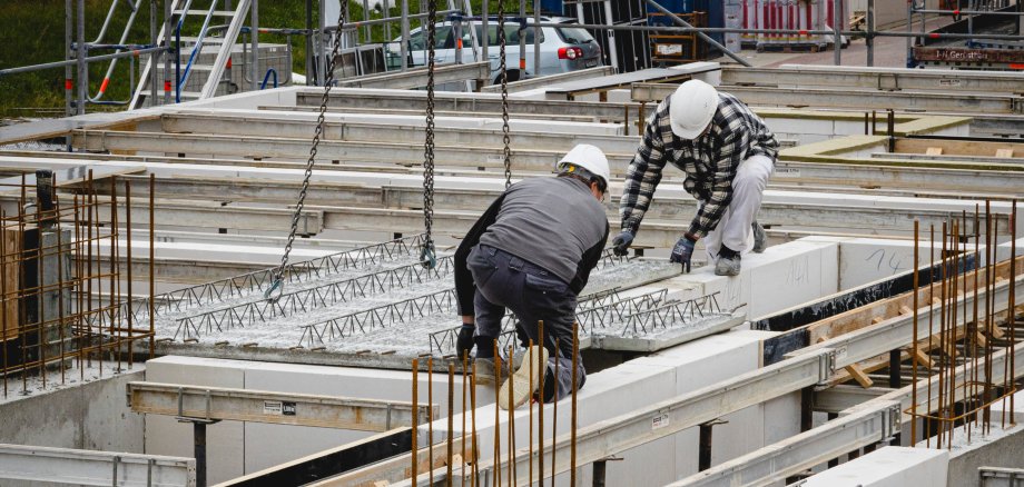 Zwei Bauarbeiter setzen Modul auf Bastelle ein