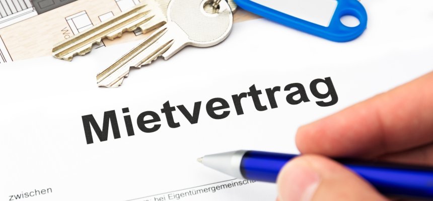 Mietvertrag mit Schlüssel, Schlüsselbund und blauen Kugelschreiber und Hand