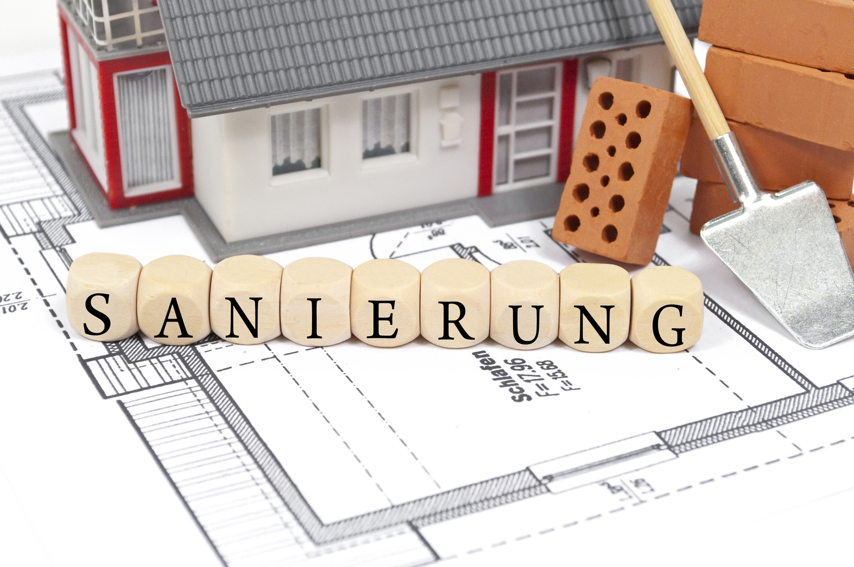 Bauplan mit Ziegelsteinen und Aufschrifft: Sanierung