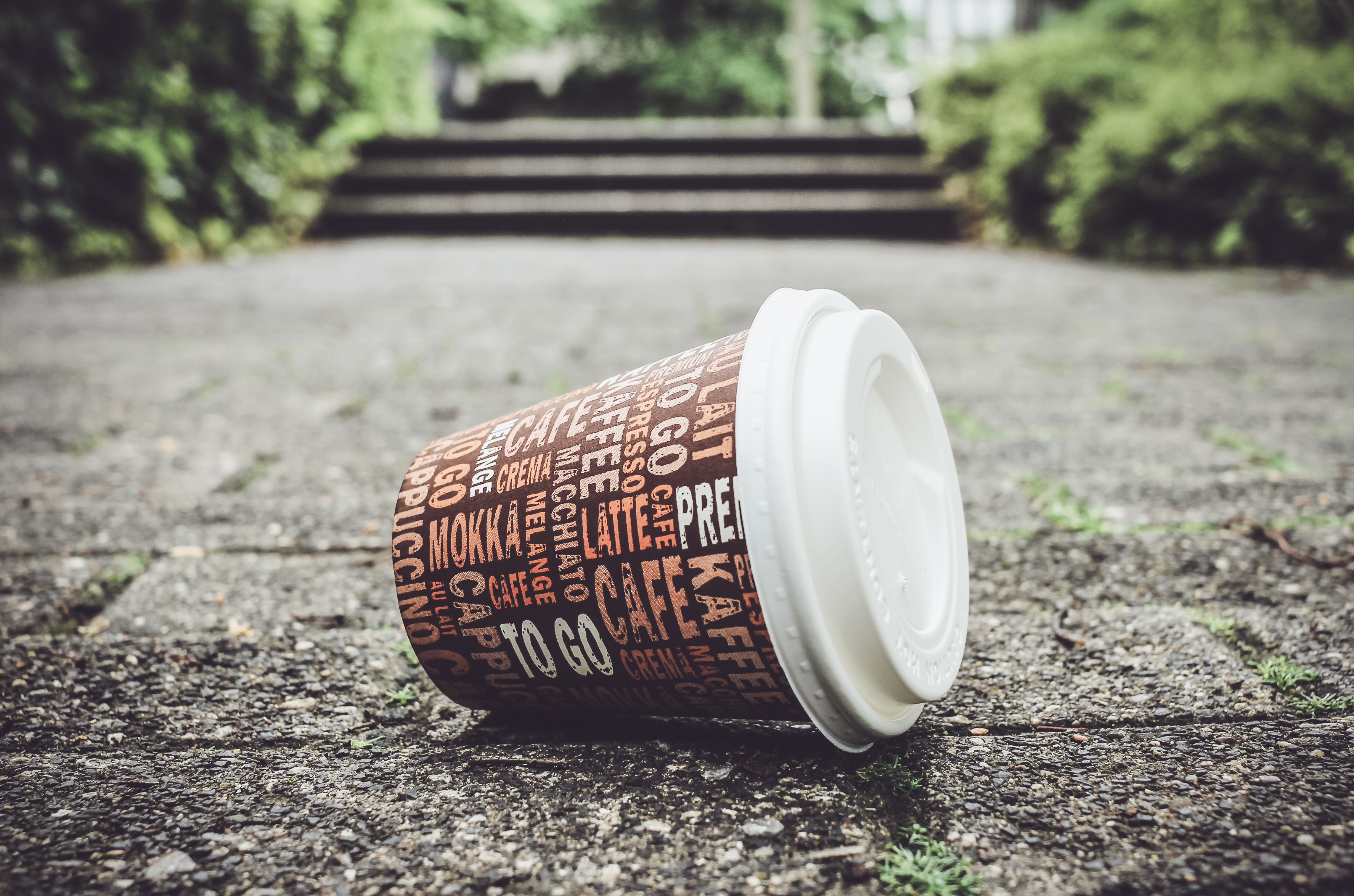 Weggeworfener leerer Kaffeebecher liegt auf Gehweg. Weggeworfener leerer Kaffeebecher liegt auf Gehweg.