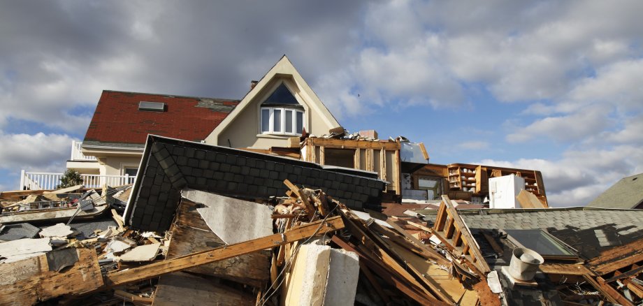 Hochwasser Schäden. Ein Berg kaputter Möbel und Schutt liegt vor einem Wohnhaus.