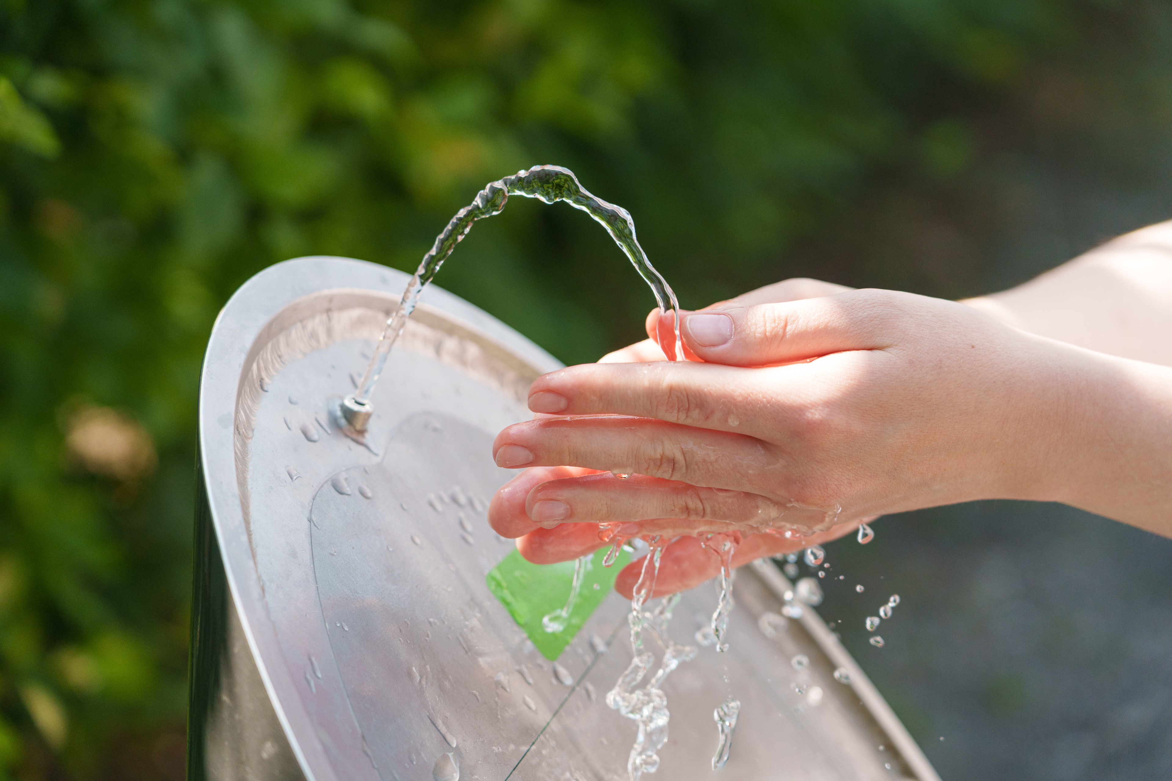 Hände fangen kühles Trinkwasser während der sengenden Sommerhitze auf.