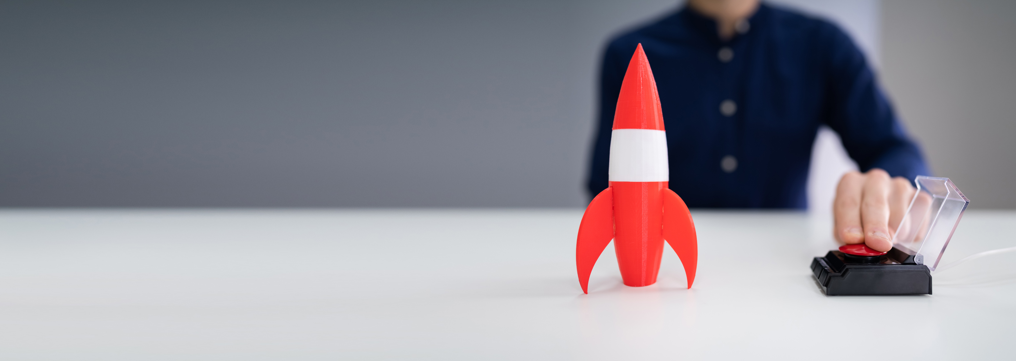 Mann drückt auf roten Knopf und rote Spielzeug Rakete steht vor ihm, die mit Kabel verbunden ist. Mann drückt auf roten Knopf und rote Spielzeug Rakete steht vor ihm, die mit Kabel verbunden ist.