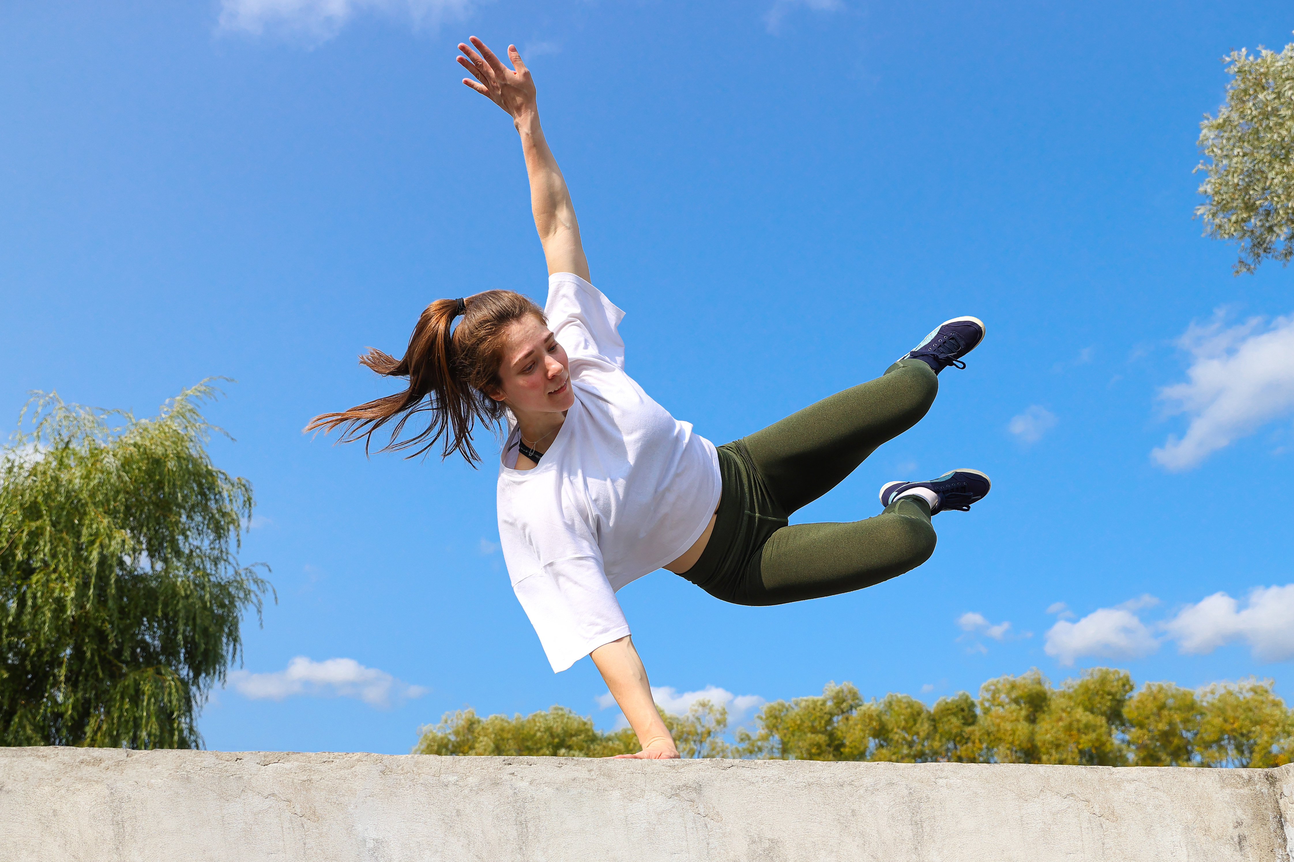 A girl jumps over a wall on a sports street playground A girl jumps over a wall on a sports street playground