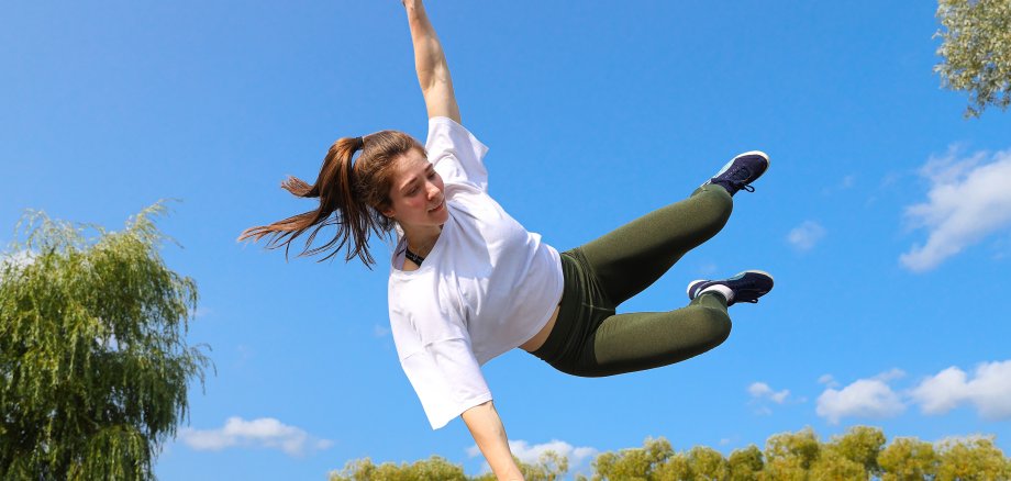 A girl jumps over a wall on a sports street playground