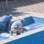 Zwei Männer, die an einem Boden eines Schwimmbeckens arbeiten. 
