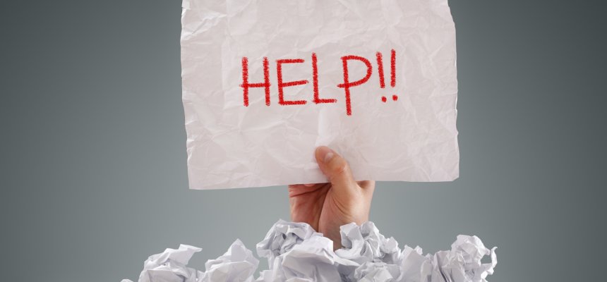 Person begraben in einem Haufen von Papier mit einem Schild mit der Aufschrift "Hilfe" in der Hand
