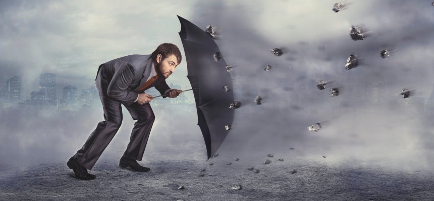 Geschäftsmann schützt sich selbst mir Regenschirm vor Gesteinsbrocken