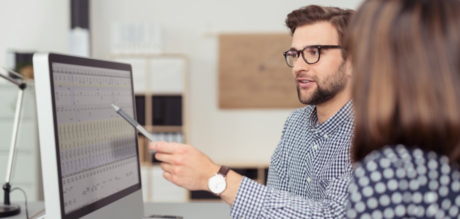 Geschäftsmann erklärt Kollegin etwas am Computer