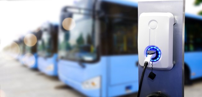 Stromsäule zum Aufladen von Elektrobussen mit vielen parkenden Elektrobussen im Hintergrund