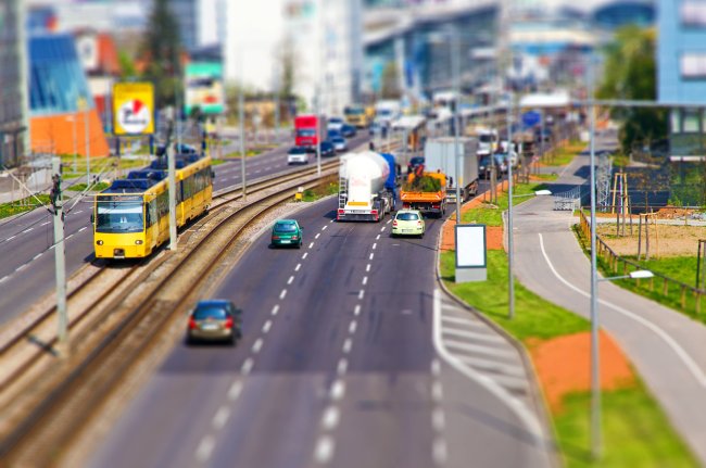 Tageslicht Foto von einer dreispurigen Straße, die parallel zu einer Straßenbahnlinie verläuft.